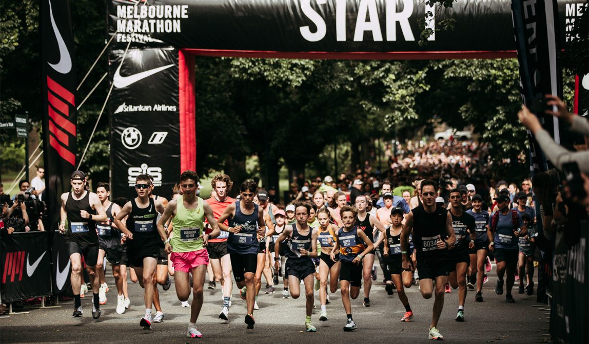 Runner crossing the finish line near the MCG at the Nike Melbourne Marathon Festival 2026 with Team Variety