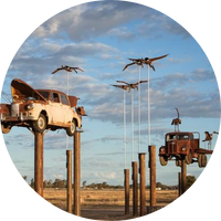 Hoisted cars and artificial birds make an art installation, pictured against a cloudy blue sky Hoisted cars and artificial birds make an art installation, pictured against a cloudy blue sky