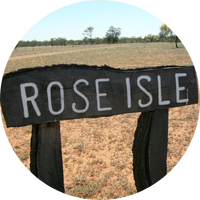 black sign pictured against a red dirt background. The sign reads 'ROSE ISLE' in white writing black sign pictured against a red dirt background. The sign reads 'ROSE ISLE' in white writing